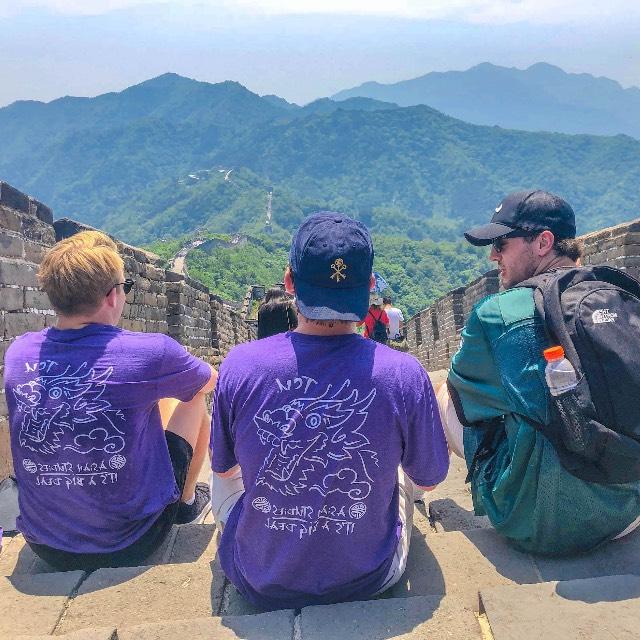 Three students sit atop the Great Wall of China