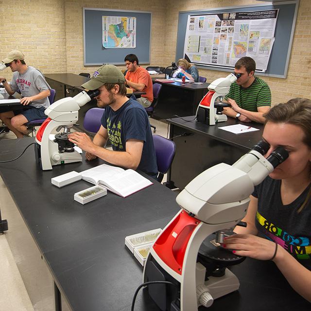 地质学学生在显微镜下研究样品